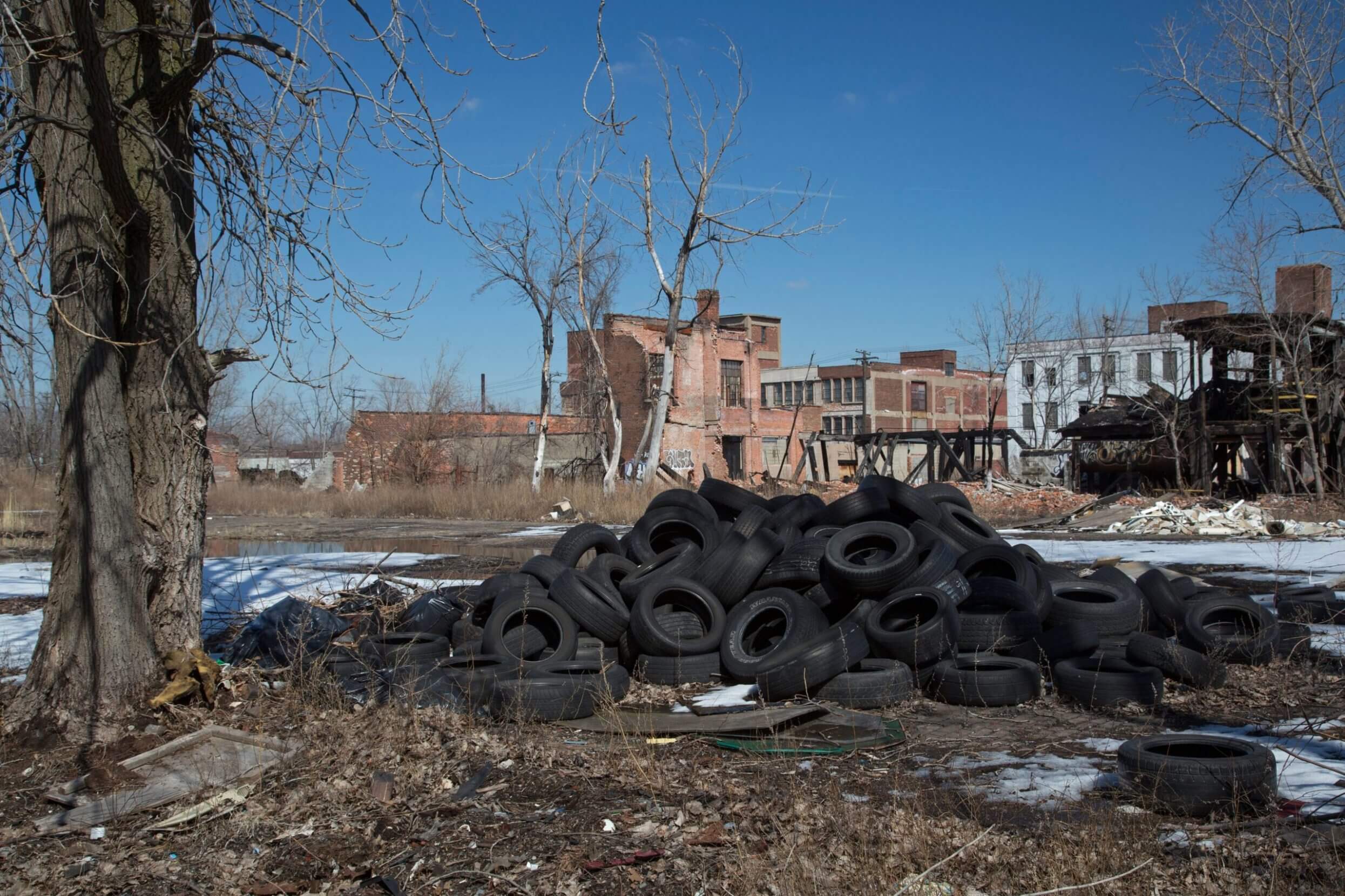 D4BN3B Detroit, Michigan - Used tires dumped on a vacant lot next to derelict buildings.