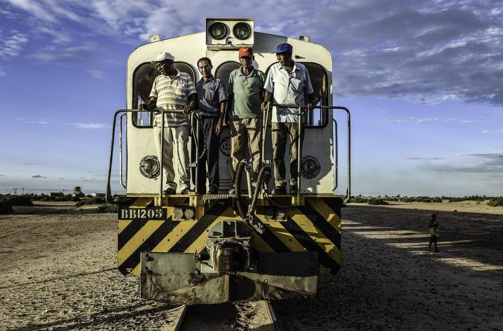 The train's drivers and mechanics pose during a stop in the desert, just before sunset