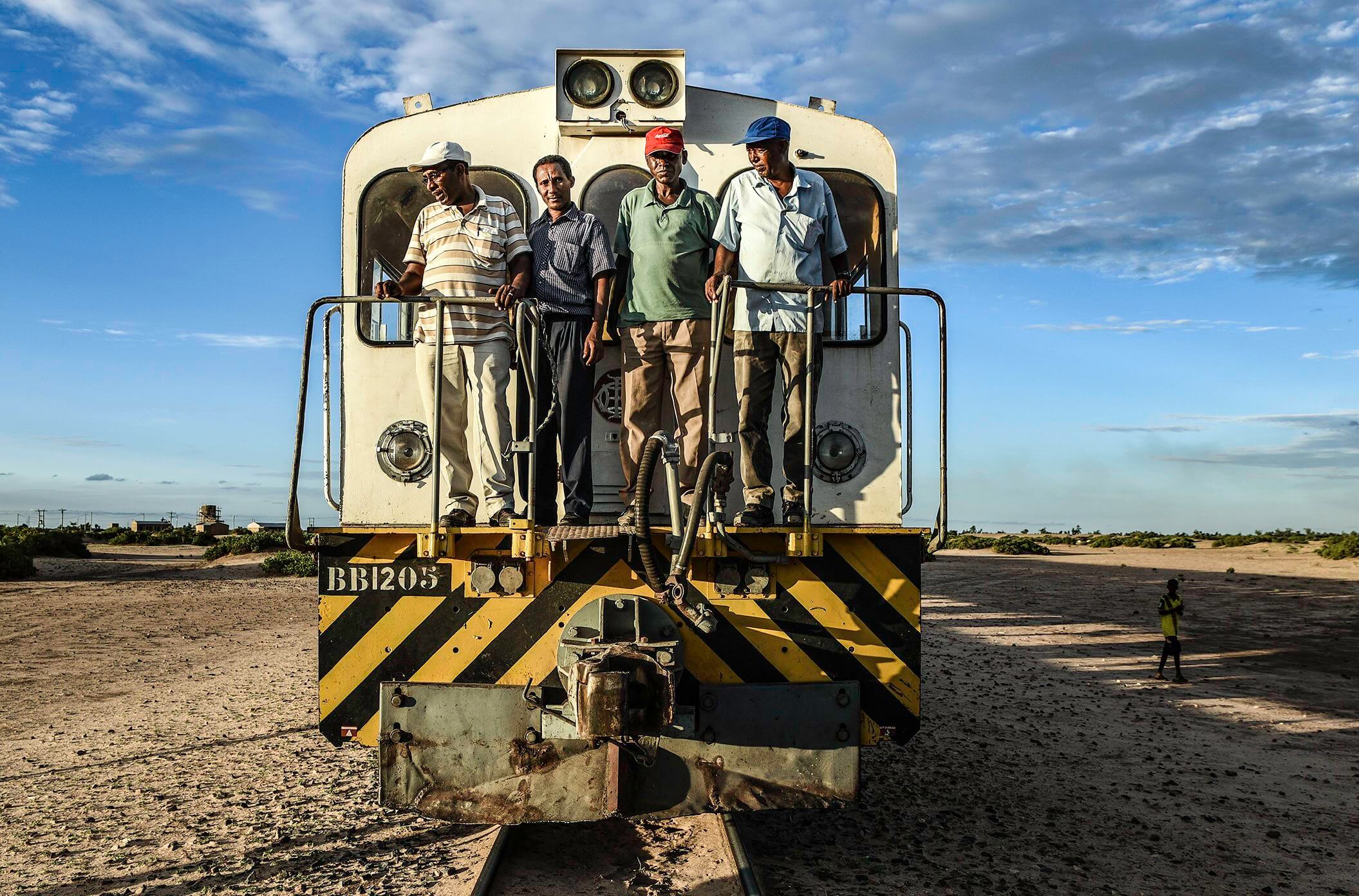 The train's drivers and mechanics pose during a stop in the desert, just before sunset