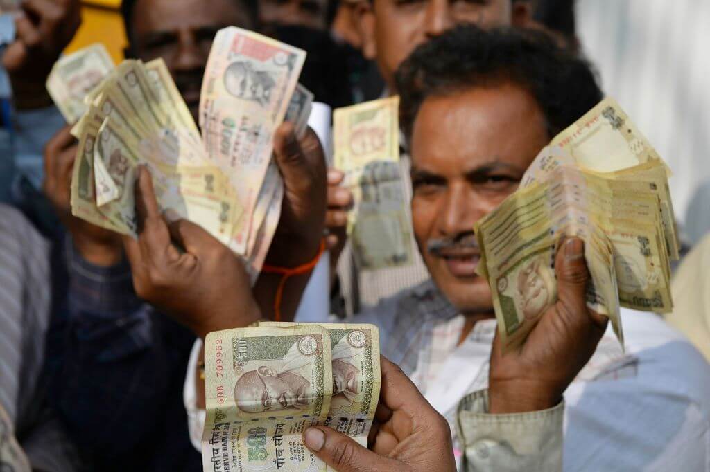 People waiting to exchange demonitised Indian currency, show their old 500 and 1000 Rupee notes near the closed gates of Reserve Bank of India in Bangalore on January 2, 2017 after acceptence of the banned notes at banks and RBI ended two days ago. / AFP PHOTO / Manjunath KIRAN
