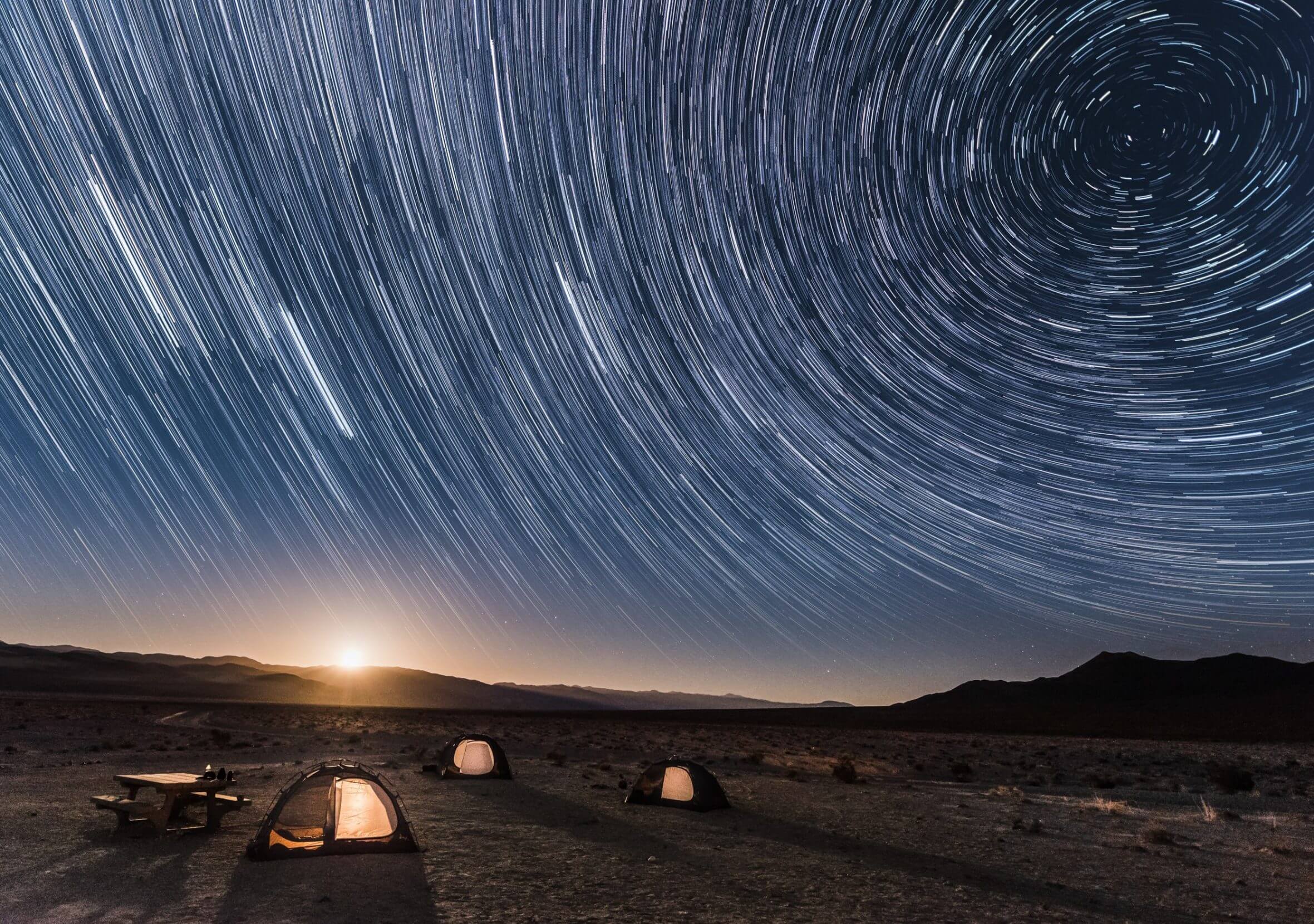 Star trails with the moon setting over a campsite in Death Valley.