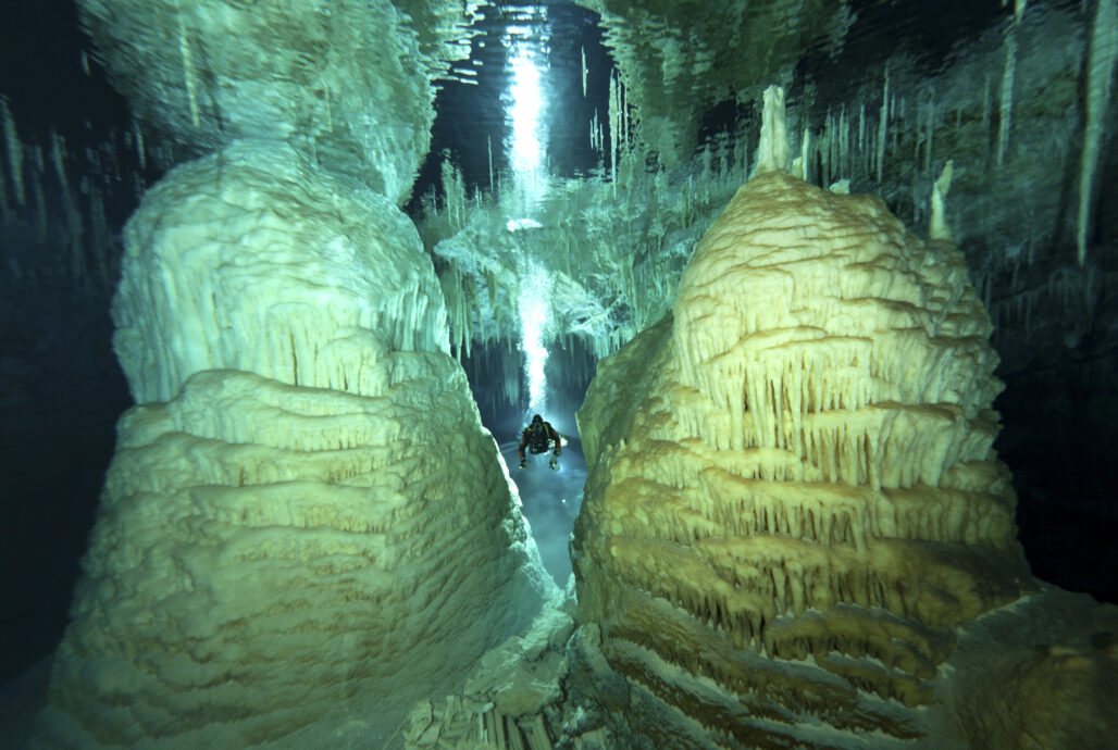 A diver between two underwater cave formations.