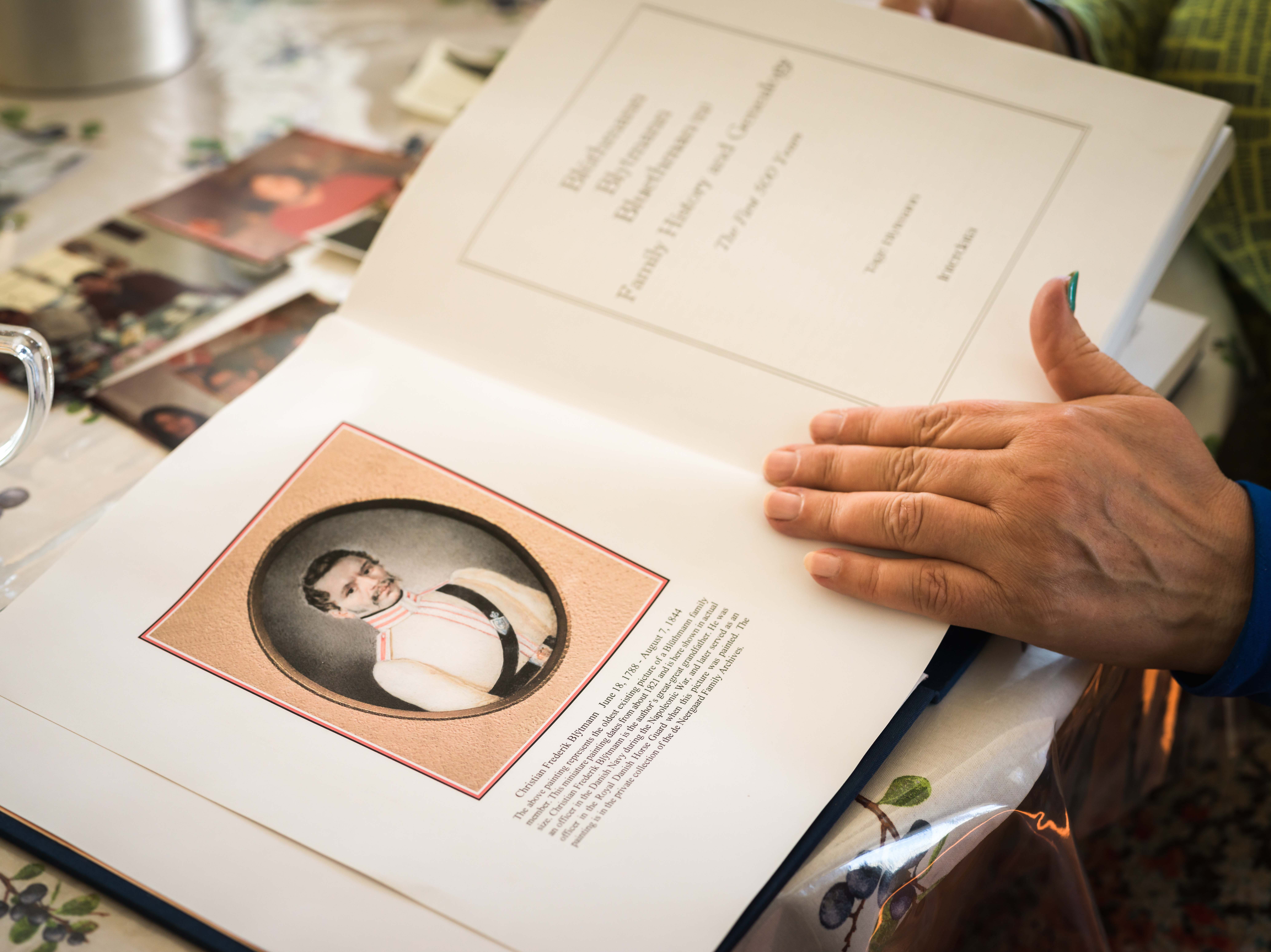 A woman's hand holds open the pages of a photo album.