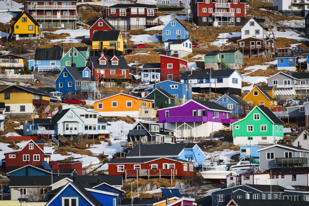 Brightly colored houses on a rocky hillside dusted with snow.