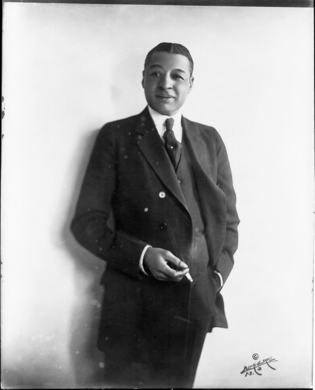 Portrait of a Black man in an elegant suit, cigarette in hand.
