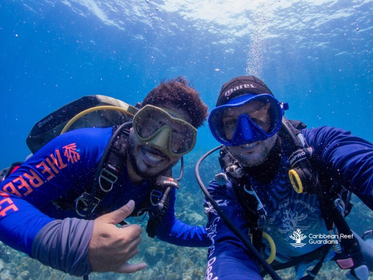 Two scuba divers take a selfie underwater.