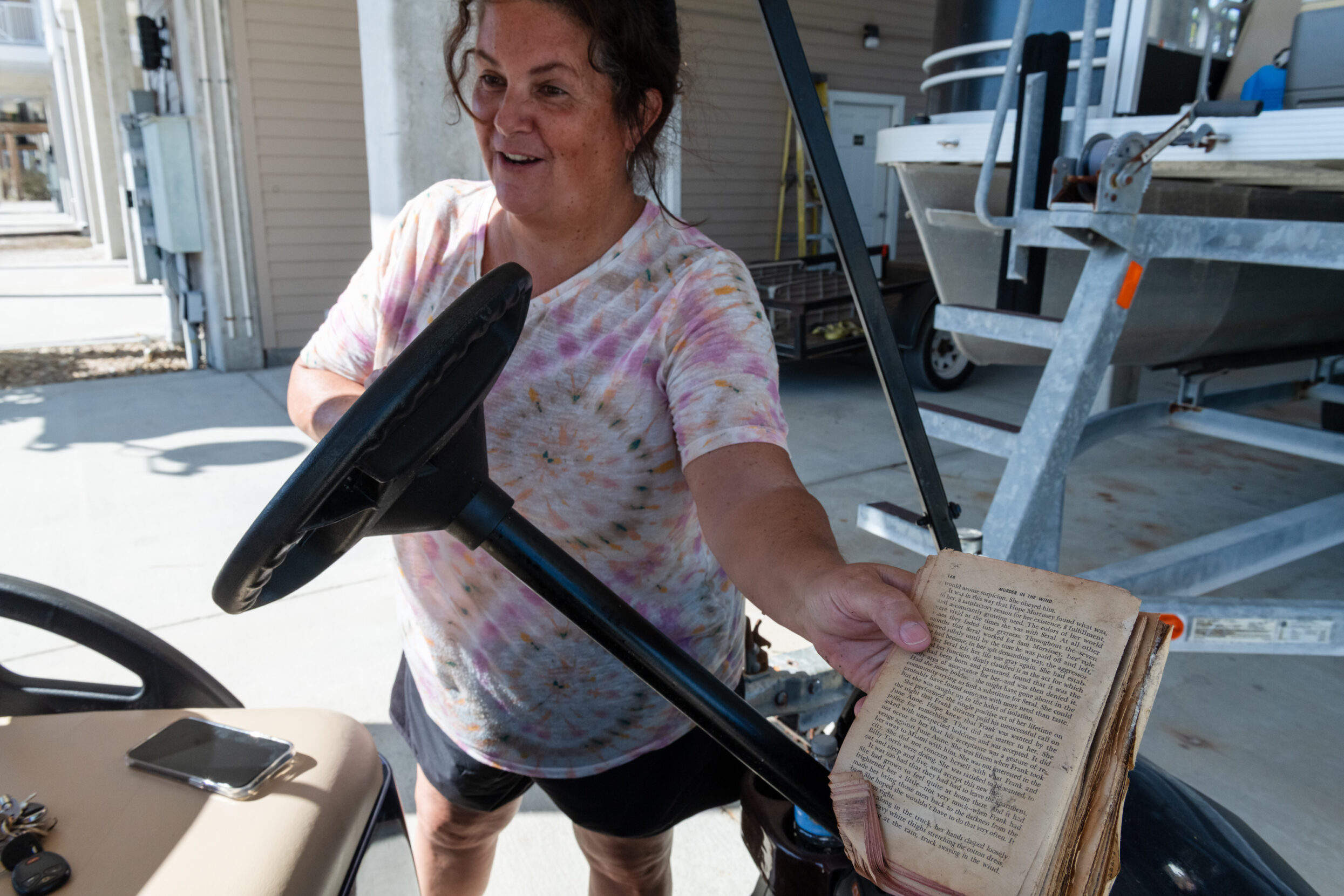 a woman stands next next to a golf card holding a weathered book