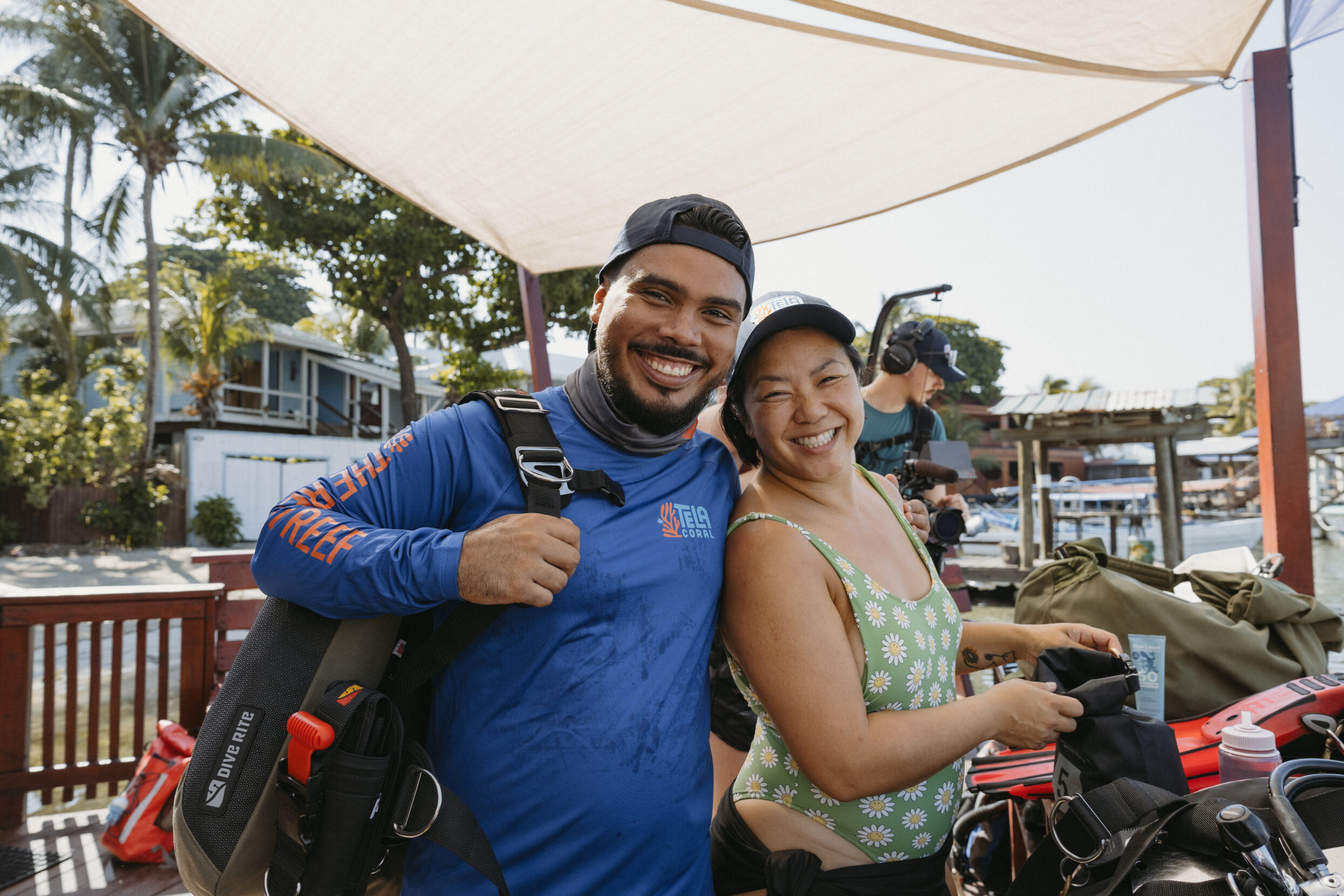 A man in a blue rashguard and a woman in a green swimsuit smile at the camera.