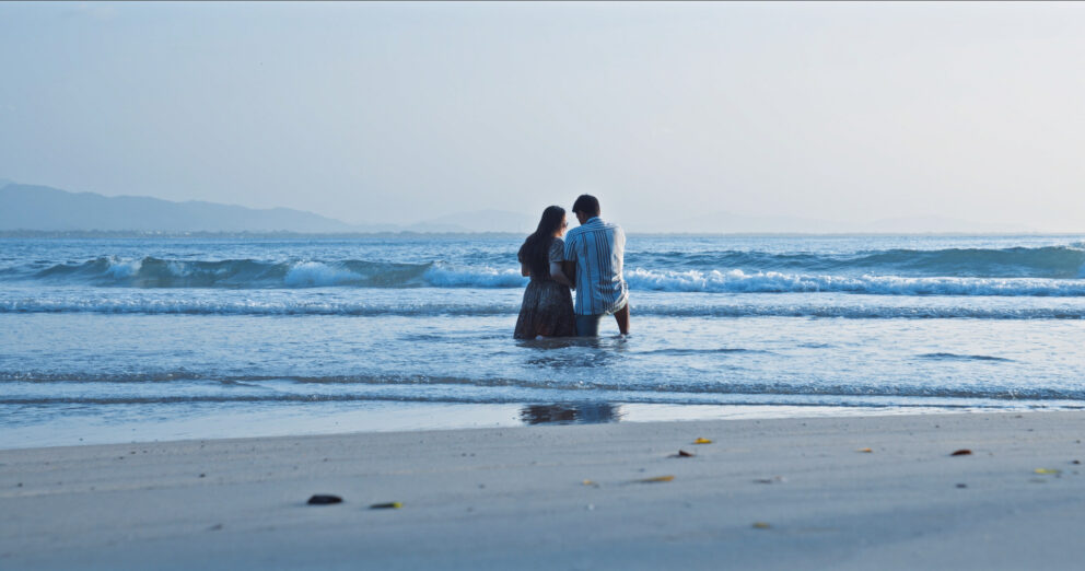 A man and woman wading into the ocean