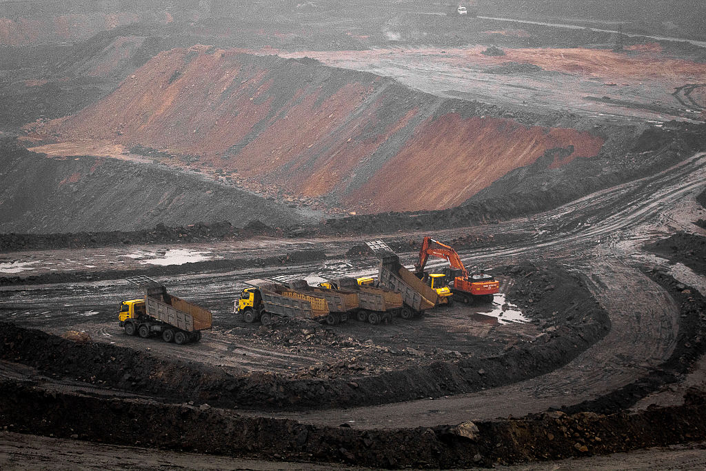 Trucks and other heavy equipment surrounded by a red and brow barren landscape